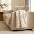 Cream cable faux fur lap throw draped over the arm of a linen sofa