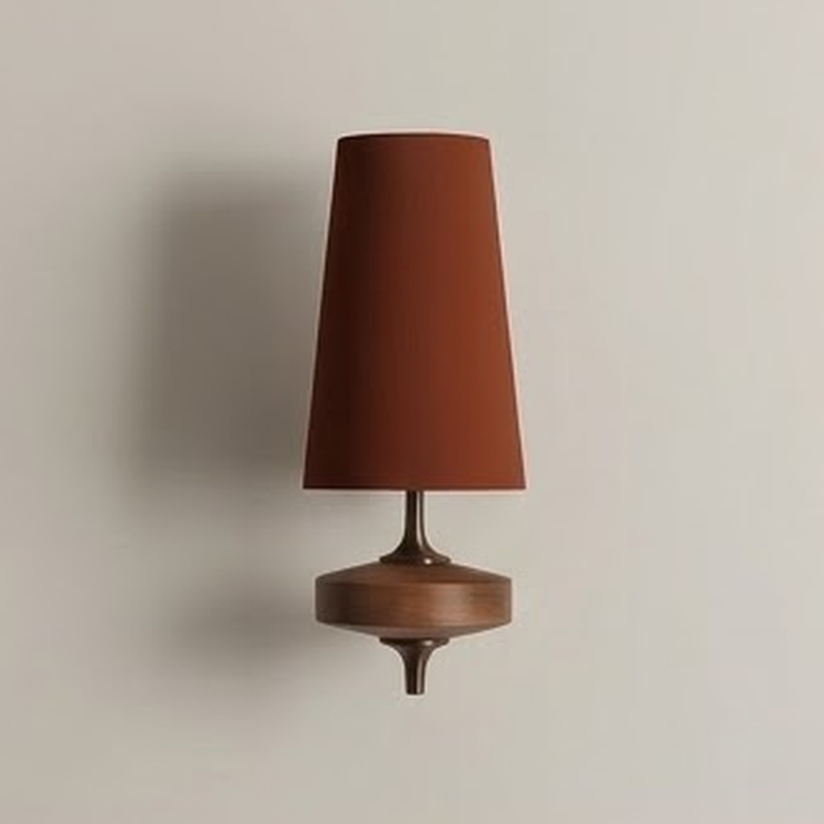 Rust fabric cone wall sconce on a turned walnut base against a pale plaster wall