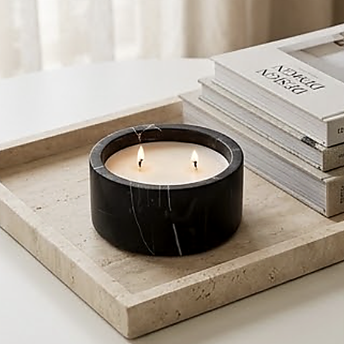 The black marble finish on a travertine tray beside stacked design books. Wax not included