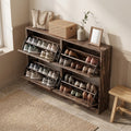 Rustic brown woven shoe cabinet with all four flip drawers open holding sneakers and heels in a hallway