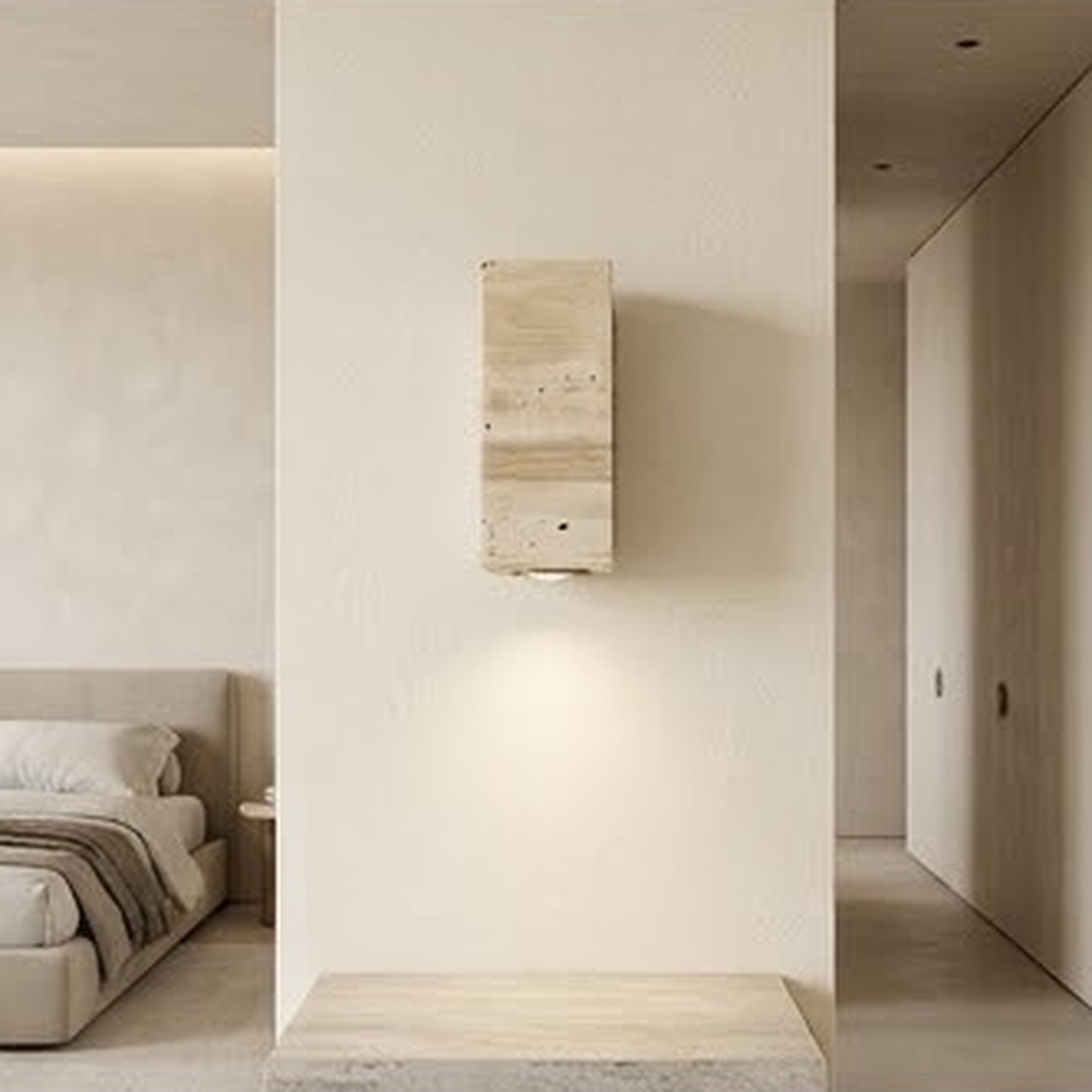 Square travertine sconce lighting a bedroom hallway wall above a stone bench