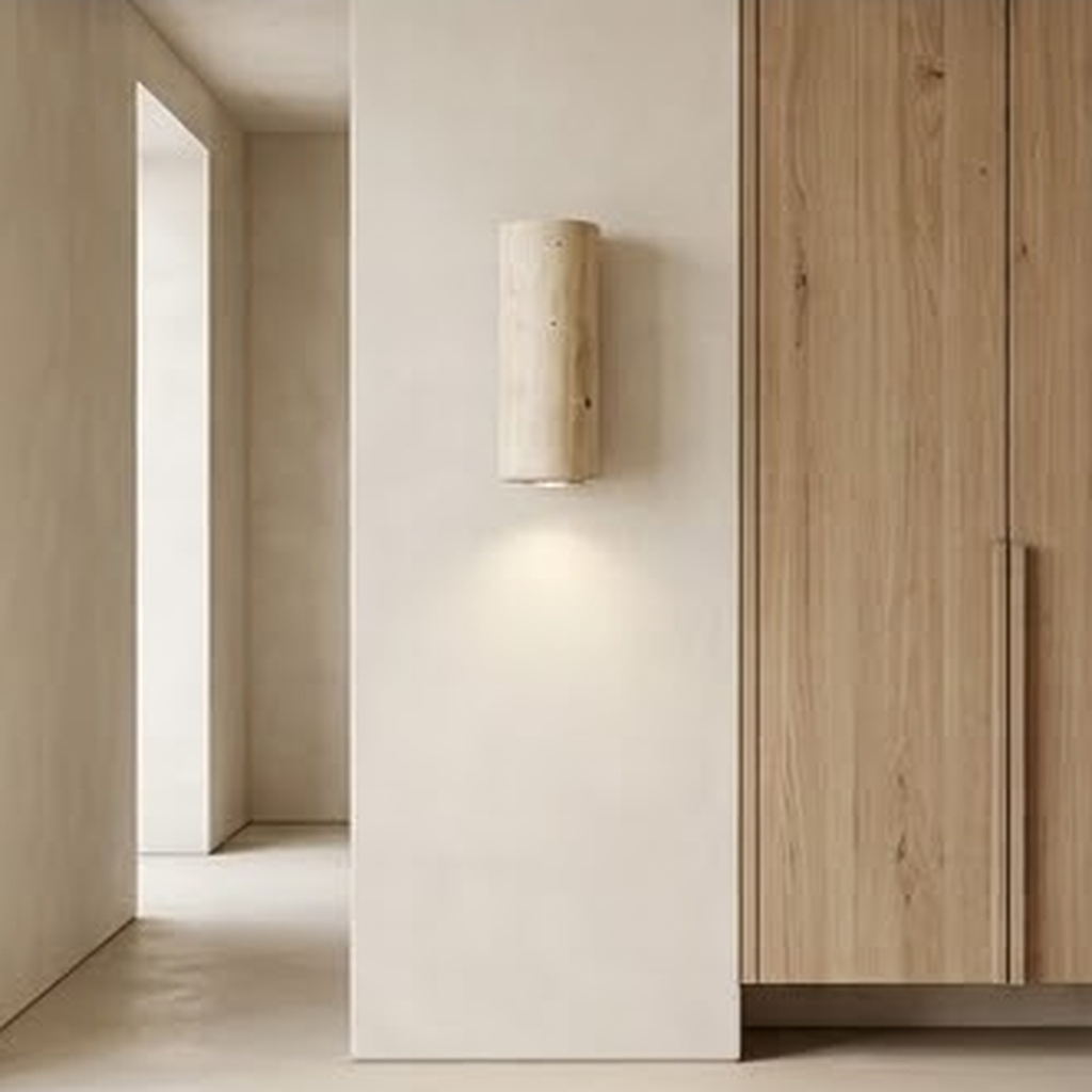 Round travertine sconce on a hallway wall next to pale oak cabinetry