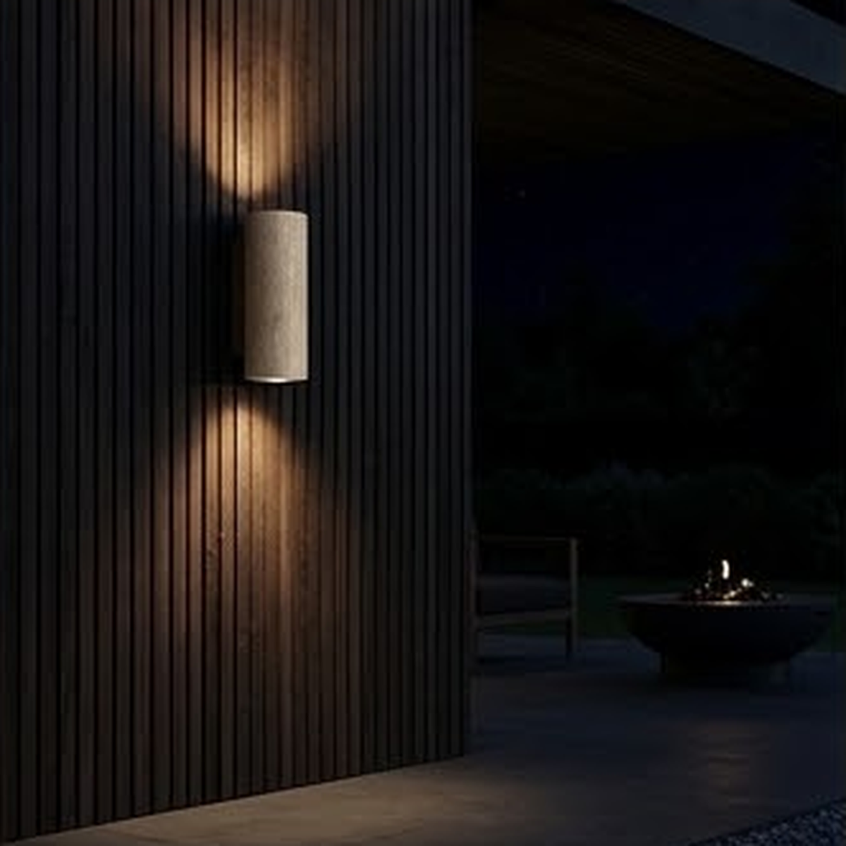 Round travertine sconce lit against dark vertical timber cladding outdoors