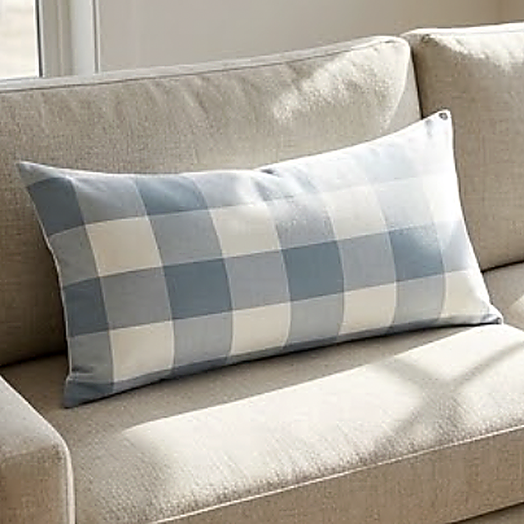 The Buffalo Check pattern, large blue and cream squares, as a 30 x 50 cm lumbar cushion on a linen sofa. Cover only
