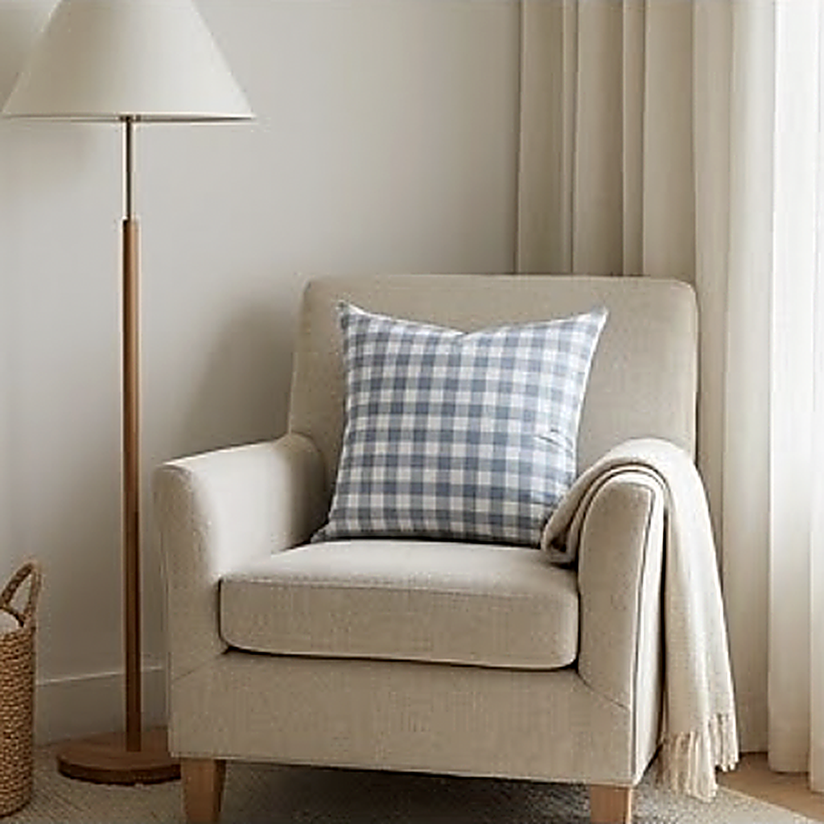 The Gingham pattern, a fine blue check, as a 45 cm square cushion on a cream armchair beside a floor lamp. Cover only