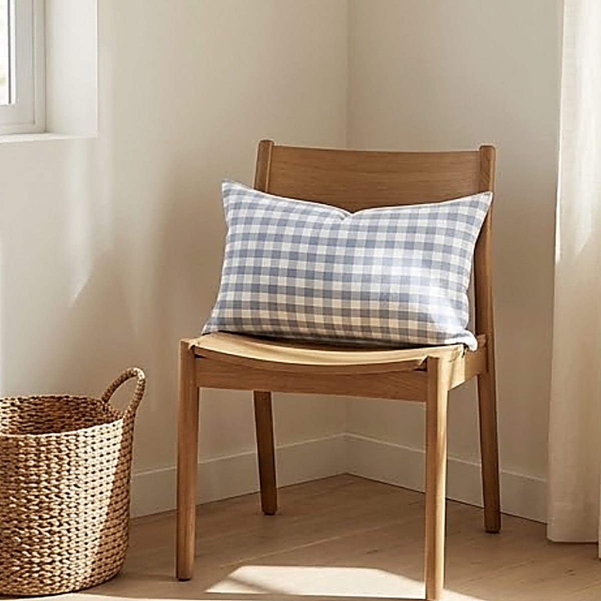 The Gingham pattern as a 30 x 50 cm lumbar cushion on an oak dining chair in a sunlit corner. Cover only