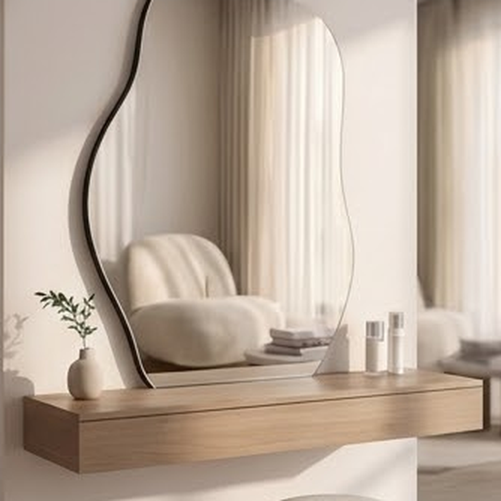 Irregular wall mirror above a floating oak vanity shelf in a soft neutral bathroom