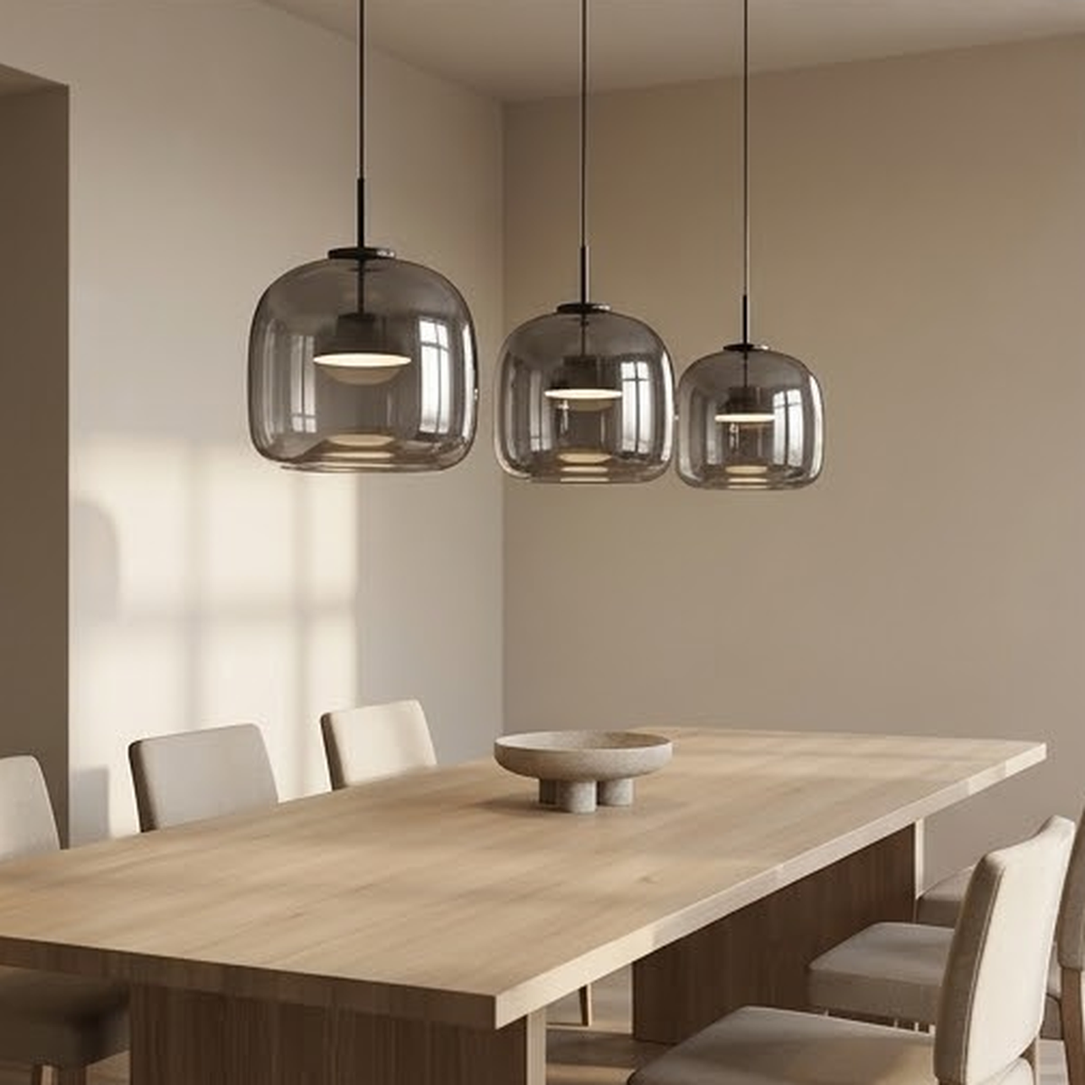 Three smoky gray glass pendants staggered over a long wooden dining table