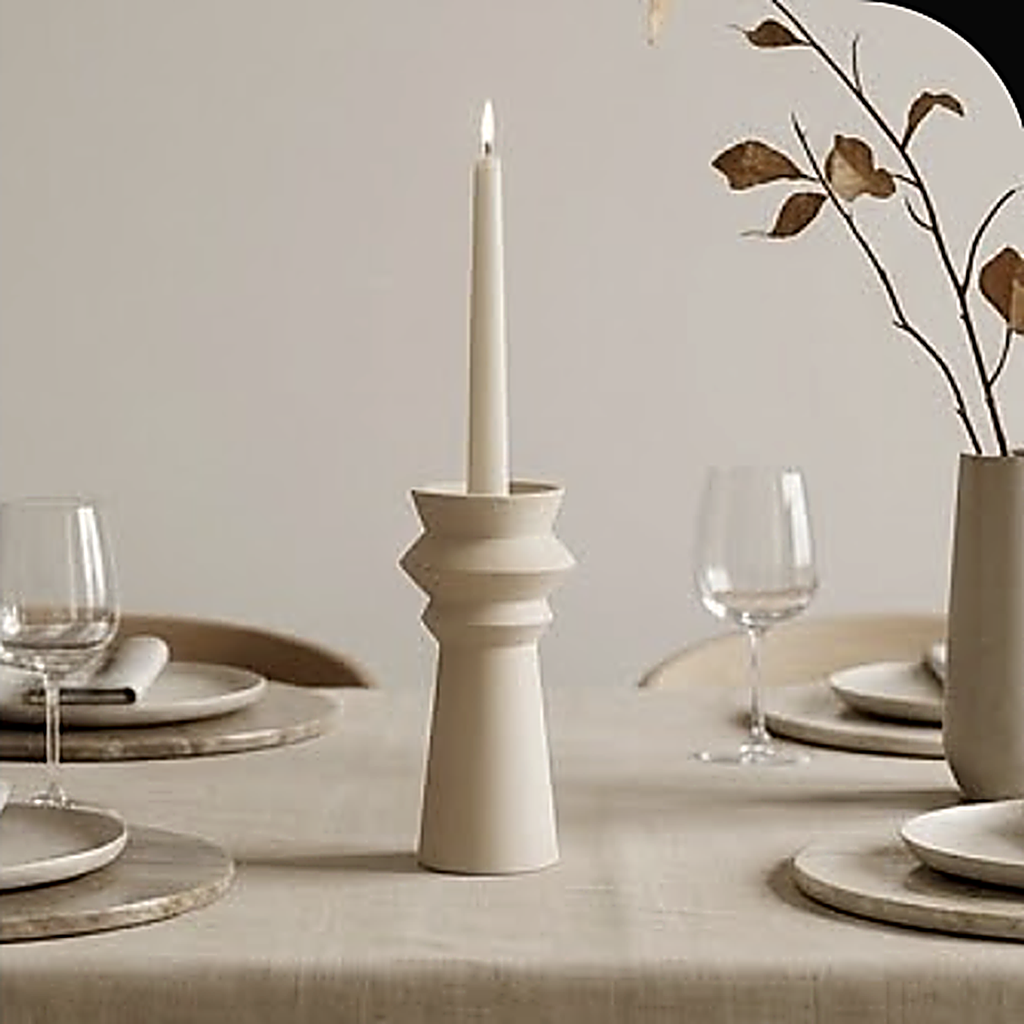 A single stepped ceramic candle holder on a set dining table between wine glasses. Styled with a taper; the maker specifies a tealight