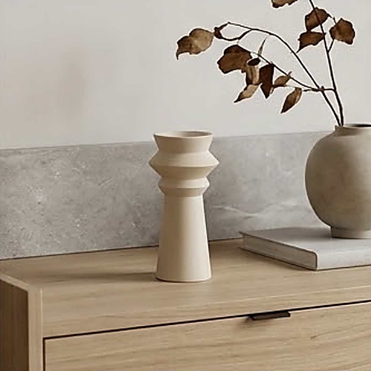 The candle holder on an oak sideboard against a stone backsplash, next to a vase of dried branches