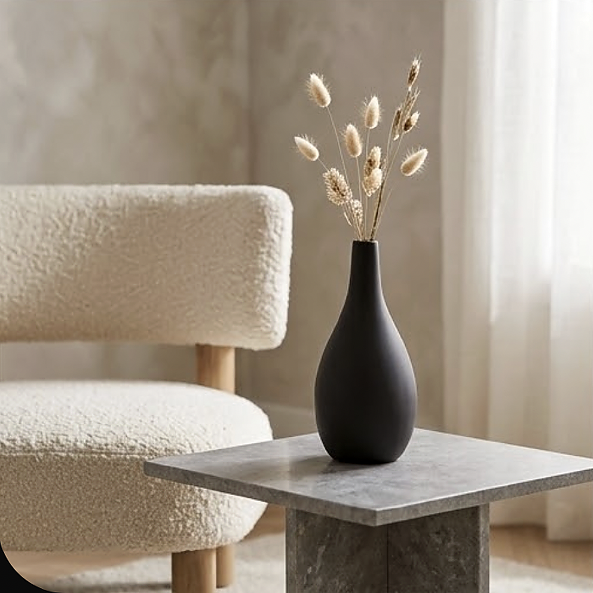 Matte black teardrop ceramic vase with a long narrow neck, 16.6 cm, holding dried stems on a grey stone side table